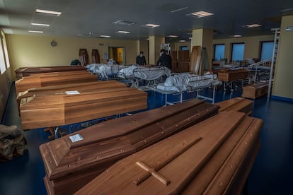 Funcionários de uma funerária preparam caixões em Bérgamo.