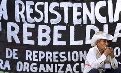 Un agricultor mexicano descansa junto a una pancarta que crítica a la OMC.