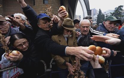 Ortodoxos macedonios tratan de alcanzar los bollos de pan navideños y ramas secas, símbolo de la Nochebuena ortodoxa, en el jardín de una iglesia en St. Kliment en Skopje (República de Macedonia). 