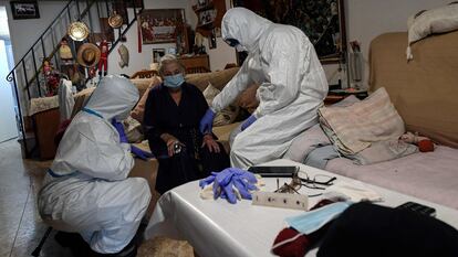 Healthcare workers examine suspected coronavirus patient at her home in Madrid.