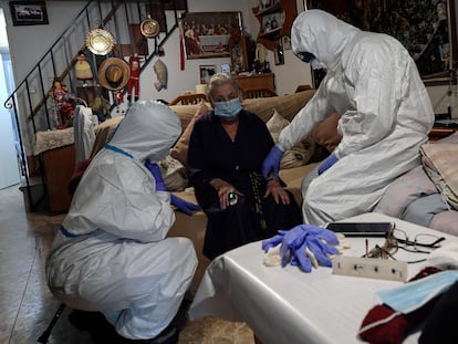 Healthcare workers examine suspected coronavirus patient at her home in Madrid.