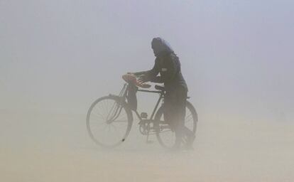 Un hombre empuja su bicicleta mientras se cubre la cara en una tormenta de arena en las orillas del Ganges en Allahabad, India.