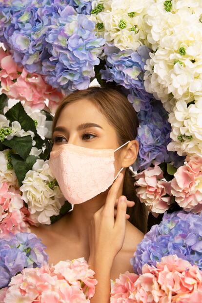 Vertical angle Beautiful asian female portrait feeling relax and smilling behind the mask with blooming flower background