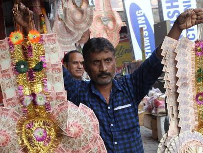 Un hombre vende guirnaldas hechas de billetes antiguos, el domingo en Jammu (India).