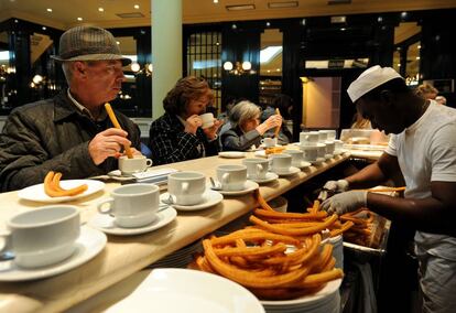 Varios clientes comen churros en un bar de Madrid.