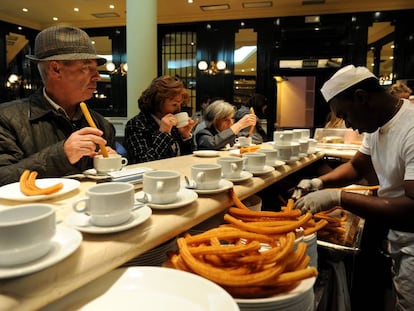 Varios clientes comen churros en un bar de Madrid.