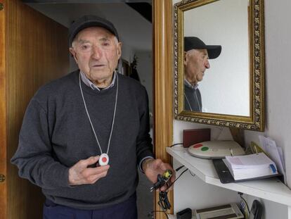 Un anciano muestra el botón de teleasistencia y la conexión de su casa, estropeados. 