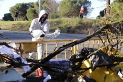 Un joven con el rostro cubierto procede a rociar con gasolina una barricada que un grupo de radicales incendiaron en la Universidad Complutense de Madrid durante los incidentes ocurridos a primera hora de la mañana.