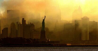 La estatua de la Libertad vista con las primeras luces desde la ciudad de Jersey, al fondo se ve la "skyline" de Manhattan entre una nube de humo, cuatro días después de que se produjeran los terribles atentados que asolaron parte de Nueva York y de Washington (Estados Unidos).