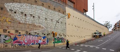 El tiburón del artista Blu, en el barrio del Carmel de Barcelona, tapado parcialmente por el Ayuntamiento para reparar el muro.