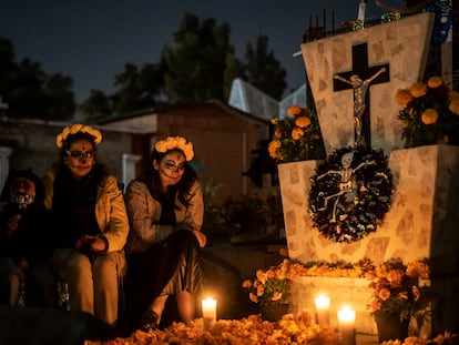 Dos mujeres y una menor junto a la tumba de un ser querido, en un panteón de la alcaldía Tláhuac, en Ciudad de México, el Día de Muertos de 2021.