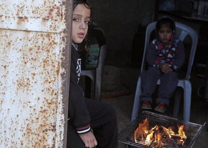 Ni&ntilde;os palestinos se calientan con un brasero en el campamento de refugiados de Al Shateaa, en Gaza. 