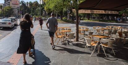 Varias personas pasan junto a una terraza vacía de la Plaza de España de Palma, en las Islas Baleares.
