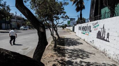 Un hombre, frente a una barda de publicidad electoral.