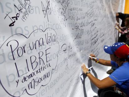 Vários oposicionistas escrevem em um mural, em um protesto em 28 de fevereiro em Caracas.