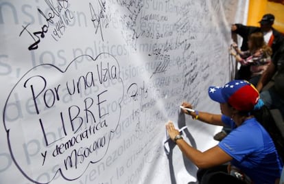 Vários oposicionistas escrevem em um mural, em um protesto em 28 de fevereiro em Caracas.