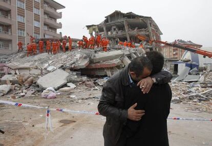 Dos hombres se abrazan frente a un edificio derruido por el terremoto en Ercis, Turqua.