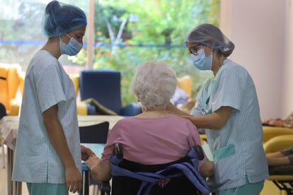 Dos sanitarias atienden a una anciana en una residencia.