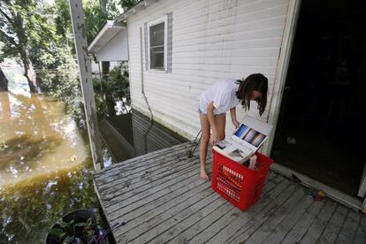 Una niña de trece años contempla sus álbumes familiares en la puerta de su casa, en St. Amant, Luisiana (EE.UU).