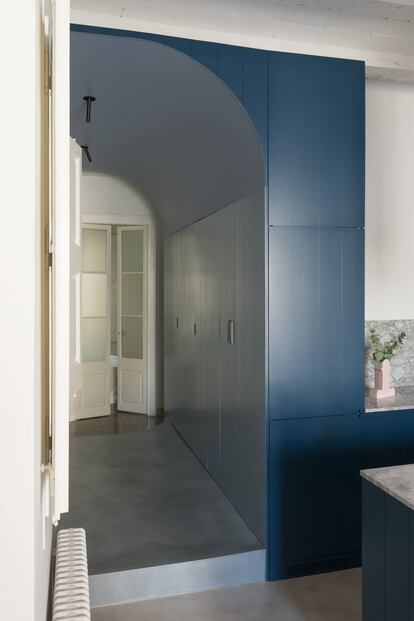 La estructura azul de los arquitectos Colombo Serboli esconde espacio de almacenaje y una puerta al baño y continúa en el mobiliario de la cocina.