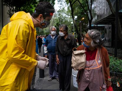 Una mujer recibe una bolsa con alimentos de un voluntario en la Ciudad de México.