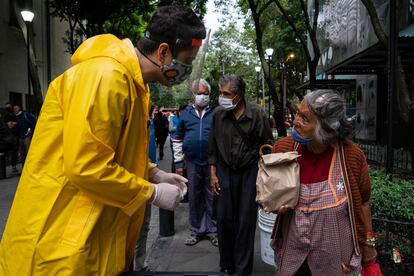 Una mujer recibe una bolsa con alimentos de un voluntario en la Ciudad de México.