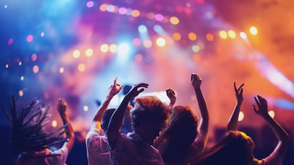 Overjoyed happy young people dancing, jumping and singing during concert of favorite group. Musical summer festival.