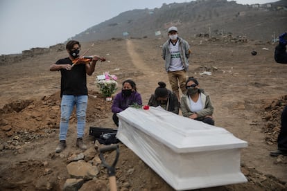 Israel Sánchez toca el violín durante el entierro de su padre, Víctor Zabala, de 73 años. Zabala murió por complicaciones tras enfermar de covid-19. La imagen fue tomada en el cementerio Nueva Esperanza en las afueras de Lima (Perú), el 28 de mayo de 2020.