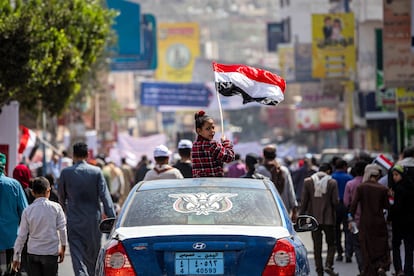 A girl holding a Yemeni flag sits in the skylight of a vehicle during a  rally in Yemen's third city of Taez on February 12, 2022,