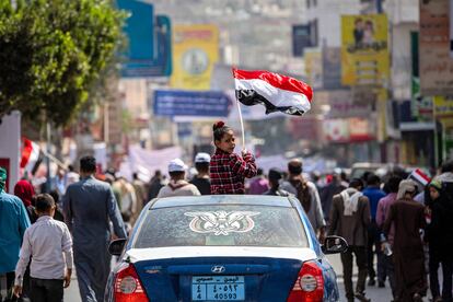 A girl holding a Yemeni flag sits in the skylight of a vehicle during a  rally in Yemen's third city of Taez on February 12, 2022,