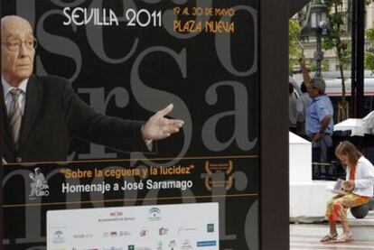 Una lectora, ayer, junto a un cartel de la Feria del Libro de Sevilla en la plaza Nueva.