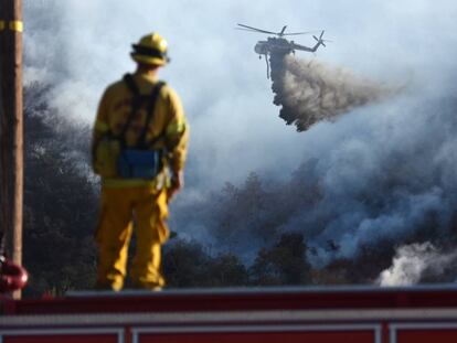Un bombero observa un helitanque luchando contra el incendio que arrasa San Bernardino. 