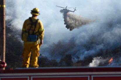 Un bombero observa un helitanque luchando contra el incendio que arrasa San Bernardino. 