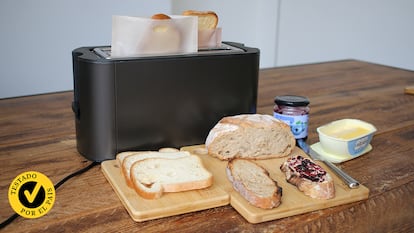 Una tostadora haciendo tostadas en bolsa con pan alrededor sobre una mesa de madera.