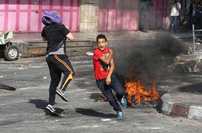 Un menor palestino corre junto a otro joven, durante los enfrentamientos con las fuerzas de seguridad israelíes en Hebrón (Cisjordania).