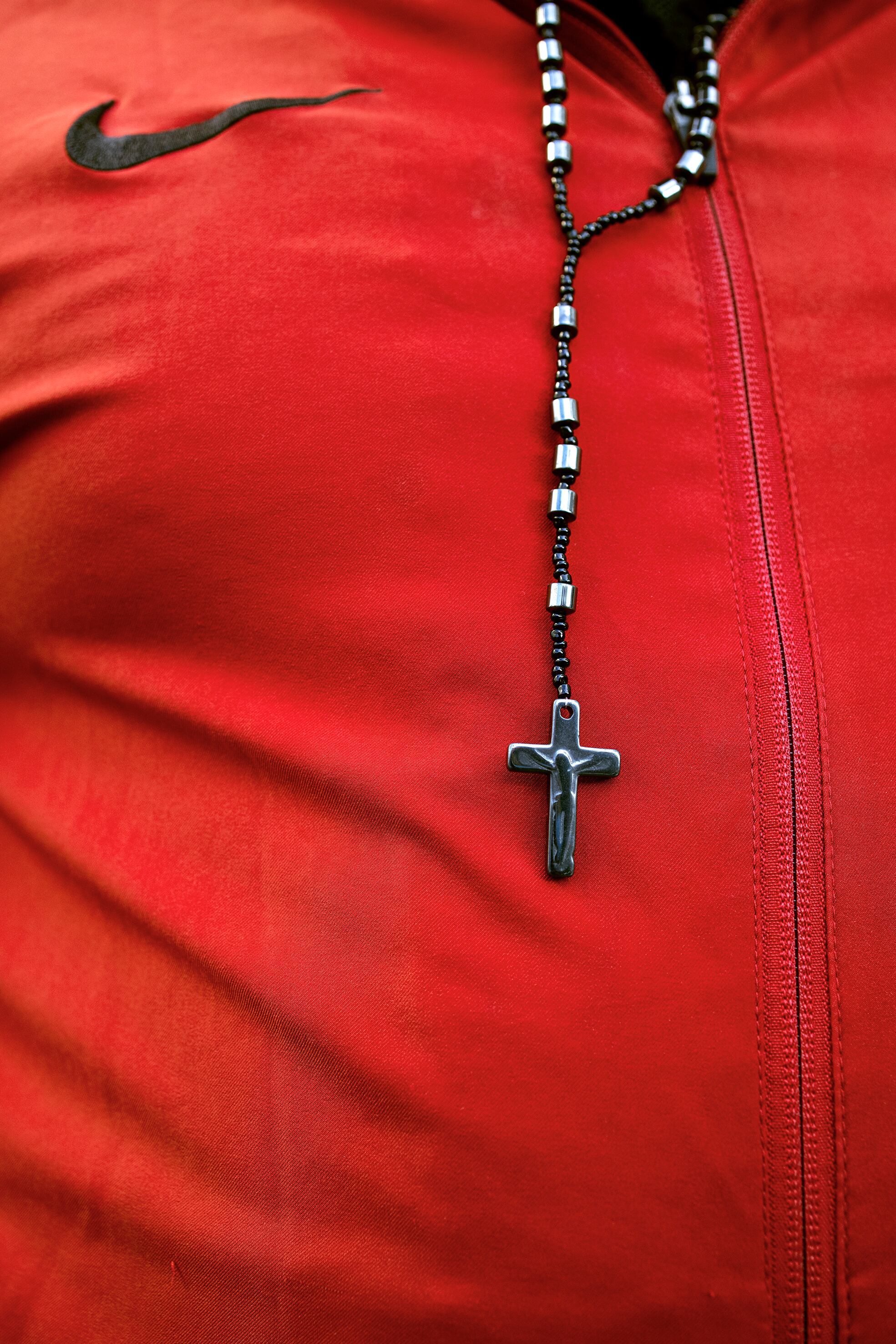 Detalle de un interno con chándal y un rosario.