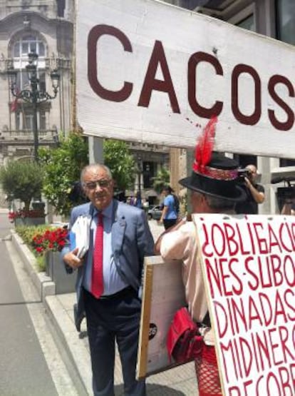 El consejero de Novacaixagalicia José Costas, ante un manifestante de las participaciones preferentes, a su salida el 28 de junio del consejo de administración de la entidad.
