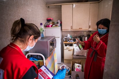 Sofía, voluntaria de Cruz Roja (izquierda), reparte alimentos en el piso en el que vive Mari Cruz (derecha), en San Sebastián de los Reyes (Madrid).