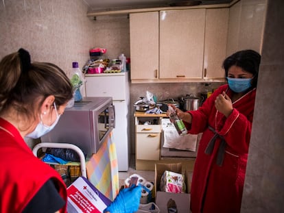 Sofía, voluntaria de Cruz Roja (izquierda), reparte alimentos en el piso en el que vive Mari Cruz (derecha), en San Sebastián de los Reyes (Madrid).