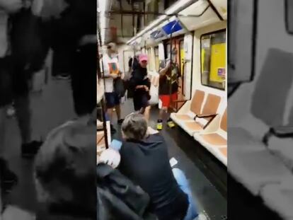 Imagen del vídeo grabado por un pasajero en el que se ve al enfermero arrodillado y al agresor con la gorra rosa.