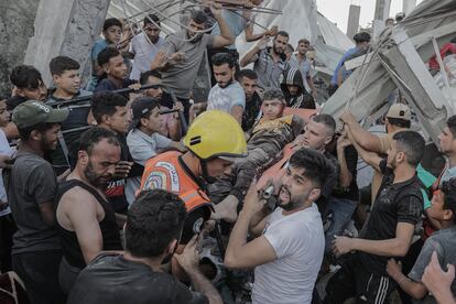 Palestinians recover a survivor among the rubble of a residential building leveled in an airstrike, in the Khan Younis refugee camp in the southern Gaza Strip, October 21, 2023.