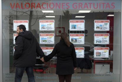 Dos jóvenes frente a una inmobiliaria.