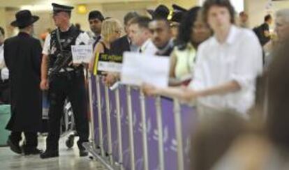 Un policía (2-i) controla la llegada de viajeros al aeropuerto de Heathrow, Londres, Reino Unido. EFE/Archivo