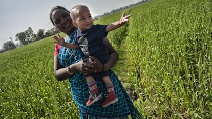 Una mujer 'santhal' sostiene a su hijo en brazos en medio de una plantación en Nepal.