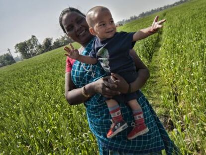 Una mujer 'santhal' sostiene a su hijo en brazos en medio de una plantación en Nepal.
