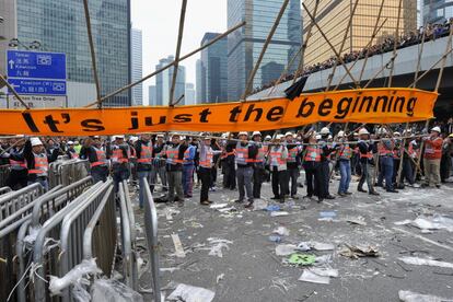 Operarios de limpieza, protegidos por la Policía, durante los trabajos para desalojar los últimos focos de las sentadas pro democracia en las calles de Hong Kong.