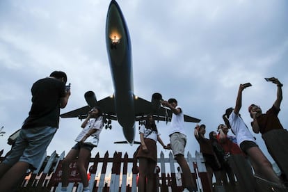 Un grupo de turistas se fotografía  bajo un avión militar C-130 durante su aterrizaje en Taipéi (Taiwan).