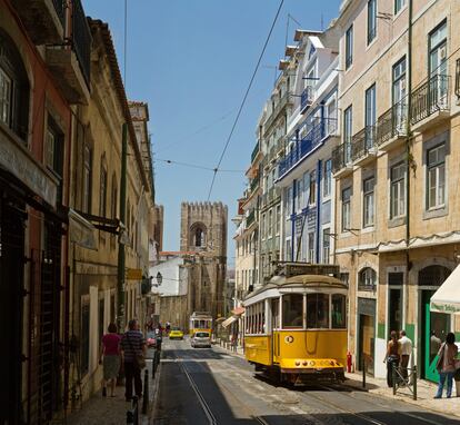 Uno de los famosos tranvías amarillos de Lisboa en una calle del barrio de Alfama. Al fondo, la Sé o catedral de Santa Maria Maior. 