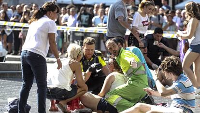 Agentes de policía y un trabajador atienden a los heridos en el atentado terrorista de La Rambla.