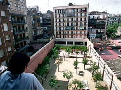 Una señora mira por el balcón de su casa hacia abajo, donde hay un patio con arbolitos. PLANO GENERAL - ESCENA